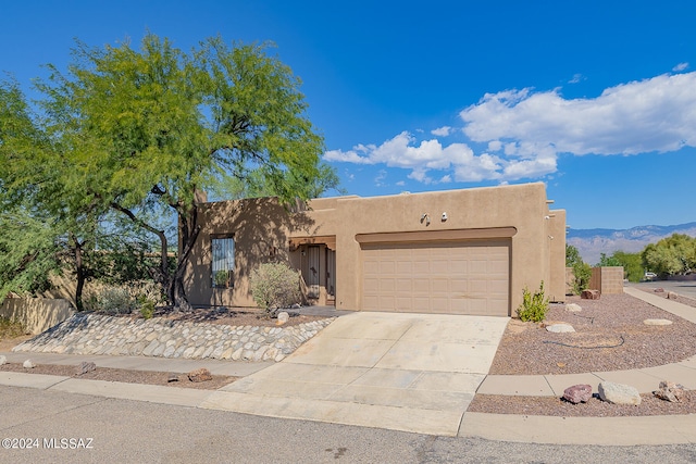 pueblo-style home with a garage and a mountain view