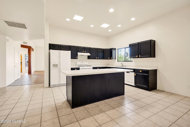 kitchen with light tile patterned floors, sink, white appliances, and a center island