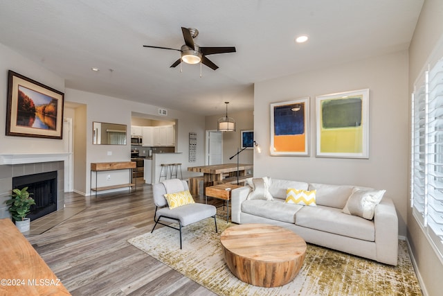 living room with a fireplace, light hardwood / wood-style floors, and ceiling fan