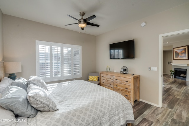 bedroom featuring ceiling fan, a fireplace, and dark hardwood / wood-style flooring