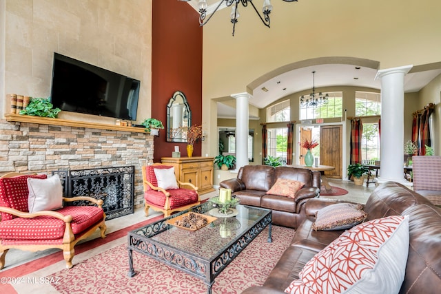 living room featuring a notable chandelier, a fireplace, decorative columns, and a high ceiling