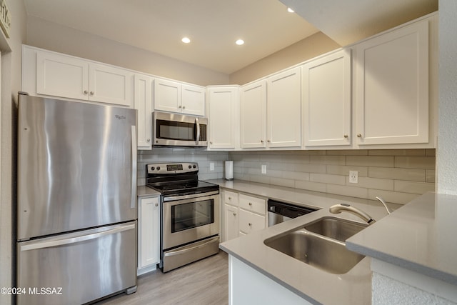 kitchen with sink, tasteful backsplash, light hardwood / wood-style flooring, white cabinetry, and appliances with stainless steel finishes