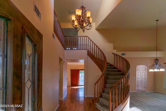 staircase with a towering ceiling and a chandelier