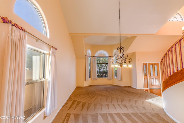 entrance foyer featuring a notable chandelier, a towering ceiling, carpet, and a wealth of natural light