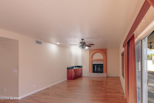 unfurnished living room featuring ceiling fan, light hardwood / wood-style floors, and a tile fireplace