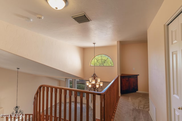 hallway with carpet flooring and an inviting chandelier