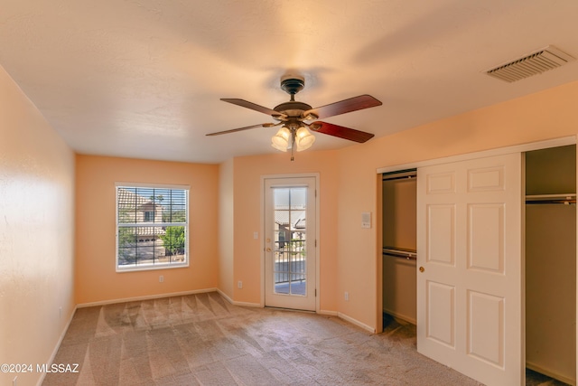 unfurnished bedroom with two closets, light colored carpet, and ceiling fan