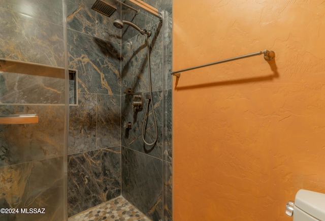 bathroom featuring a tile shower and toilet