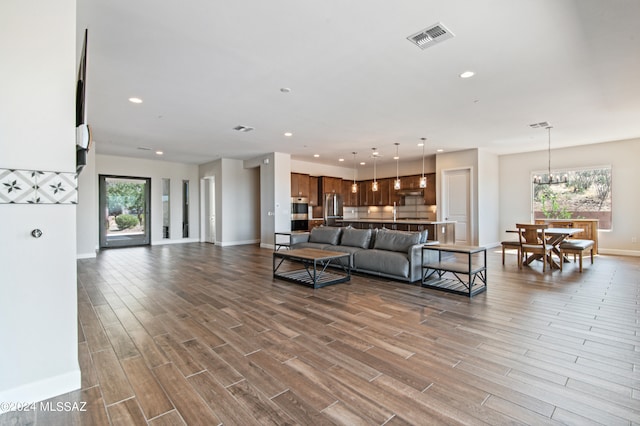 living room with a notable chandelier, hardwood / wood-style flooring, and plenty of natural light