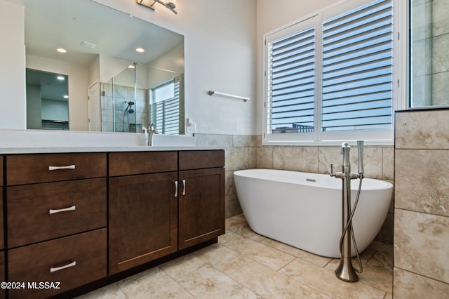 bathroom featuring a wealth of natural light, vanity, separate shower and tub, and tile walls