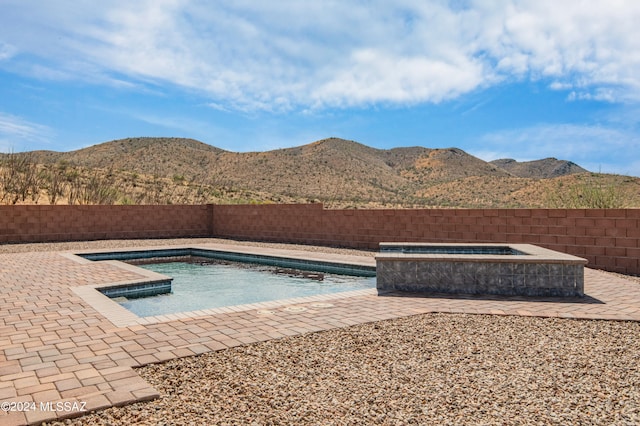 view of swimming pool with an in ground hot tub, a mountain view, and a patio area