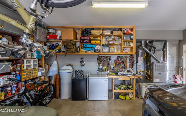 garage featuring water heater, a workshop area, and refrigerator