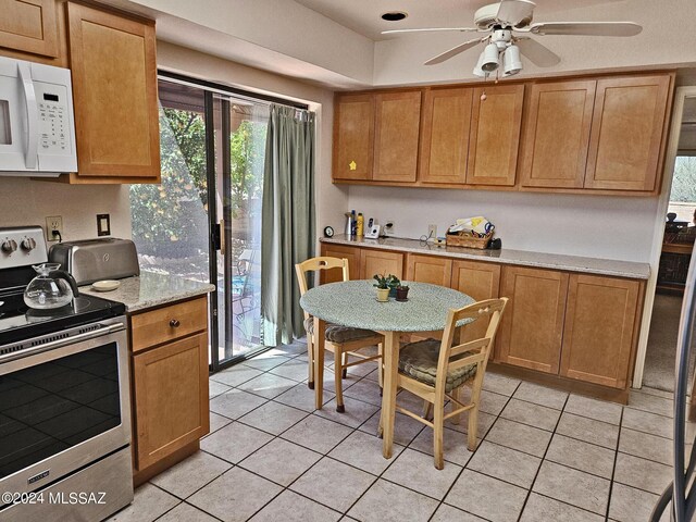 kitchen with white microwave, light tile patterned floors, light countertops, stainless steel electric stove, and ceiling fan