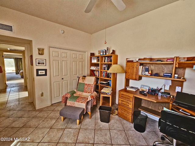 home office featuring a textured ceiling, vaulted ceiling, light tile patterned floors, and ceiling fan