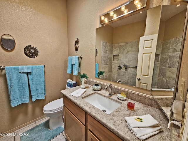 full bath featuring toilet, a textured wall, vanity, tiled shower, and tile patterned flooring