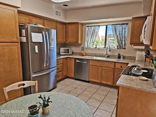 kitchen with light tile patterned floors, visible vents, appliances with stainless steel finishes, a sink, and brown cabinets
