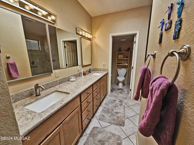full bath with double vanity, a tile shower, a sink, and toilet