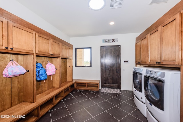 clothes washing area featuring cabinets, dark tile patterned floors, and washing machine and clothes dryer