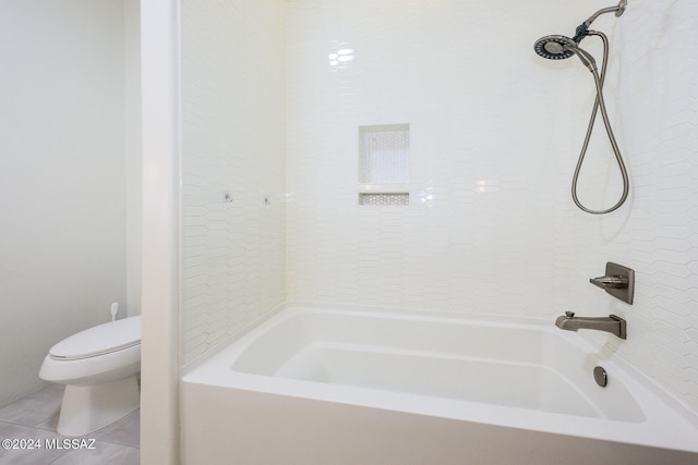 bathroom featuring tile patterned flooring, tiled shower / bath combo, and toilet