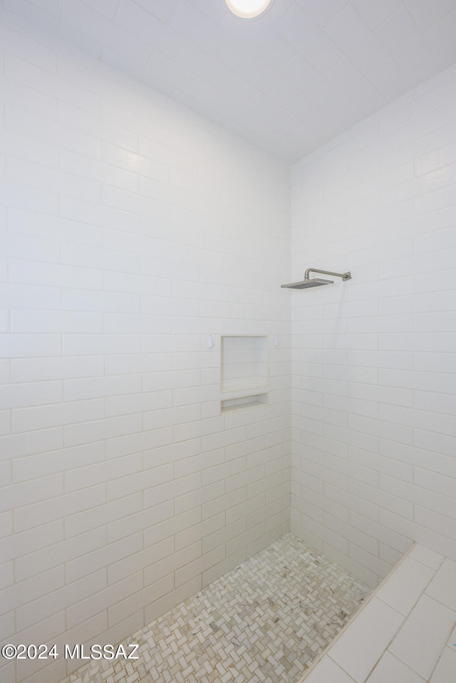 bathroom with a tile shower and tile patterned floors