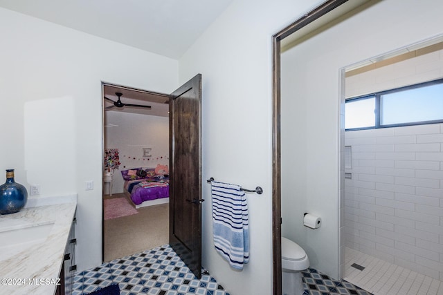 bathroom with toilet, vanity, and tiled shower