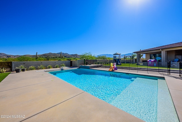 view of pool featuring a mountain view, a diving board, and a patio area