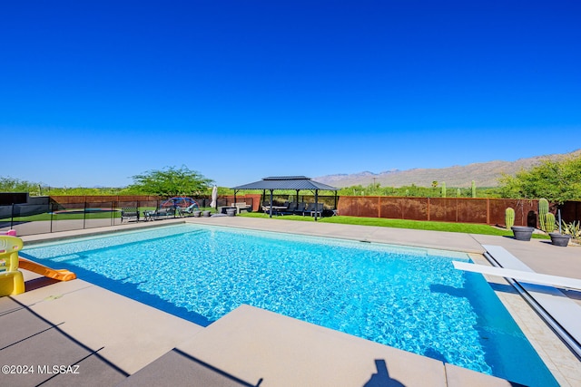 view of swimming pool with a gazebo, a mountain view, and a diving board