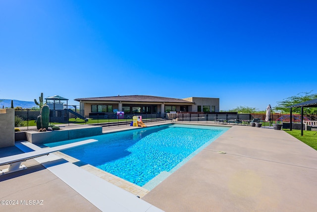 view of pool with a diving board, a playground, and a patio