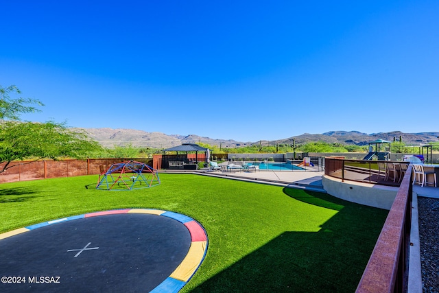 view of yard featuring a mountain view, a fenced in pool, a trampoline, a gazebo, and a playground