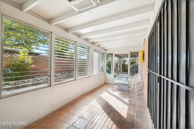 unfurnished sunroom featuring lofted ceiling with beams