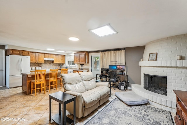 living room with light tile patterned flooring and a brick fireplace