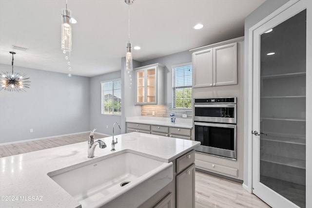 kitchen featuring double oven, light wood-type flooring, and a healthy amount of sunlight