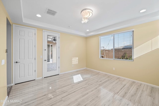 empty room featuring light hardwood / wood-style floors, a tray ceiling, and ceiling fan