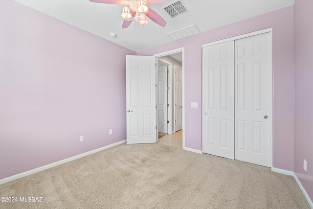 unfurnished bedroom featuring ceiling fan, light colored carpet, and a closet