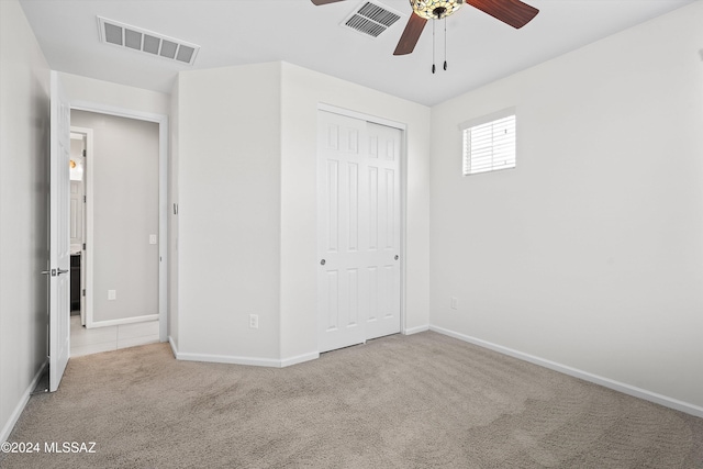 unfurnished bedroom featuring a closet, light colored carpet, and ceiling fan