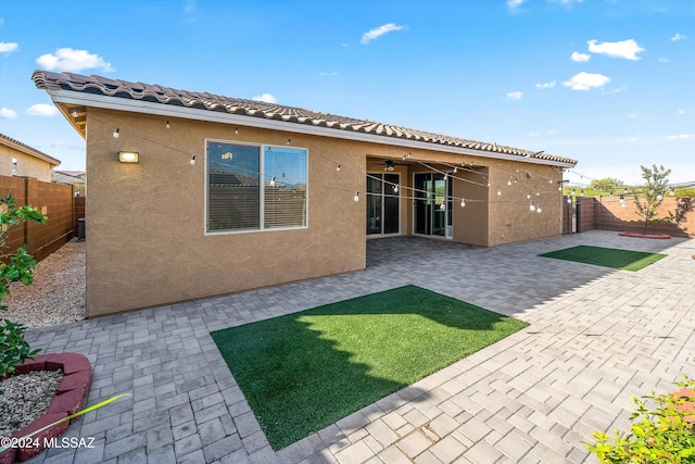 rear view of house featuring a yard, ceiling fan, and a patio area