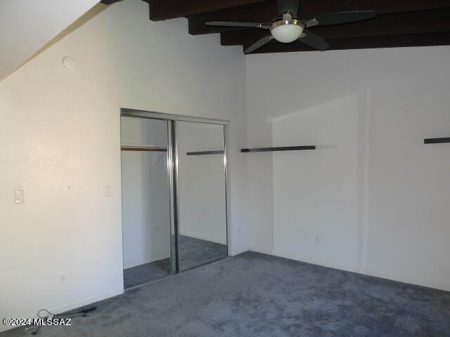 unfurnished bedroom with ceiling fan, a closet, beam ceiling, and carpet flooring