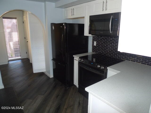 kitchen featuring tasteful backsplash, white cabinets, black appliances, and dark hardwood / wood-style flooring