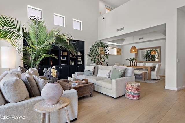 living room with a towering ceiling and light hardwood / wood-style flooring