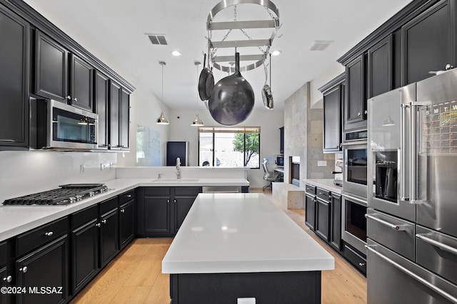 kitchen featuring pendant lighting, sink, appliances with stainless steel finishes, a center island, and light hardwood / wood-style floors