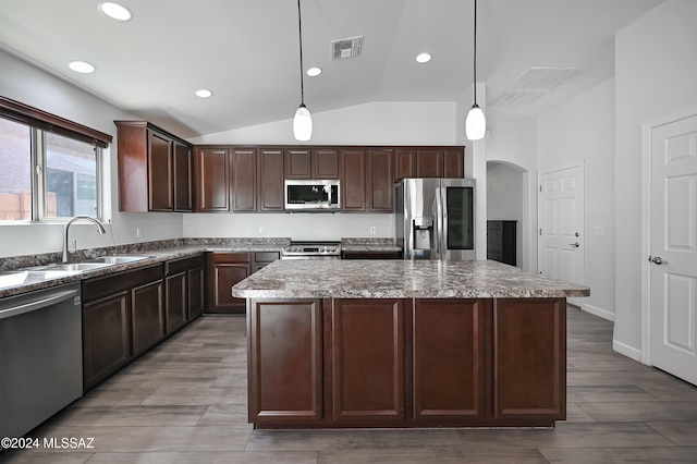 kitchen with lofted ceiling, decorative light fixtures, a center island, and stainless steel appliances