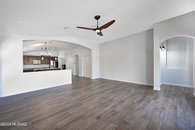 unfurnished living room with lofted ceiling, dark wood-type flooring, and ceiling fan with notable chandelier