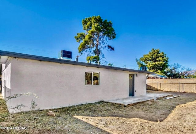 rear view of house featuring a patio, stucco siding, cooling unit, and fence