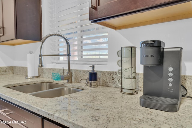 kitchen featuring dishwasher, sink, and light stone counters