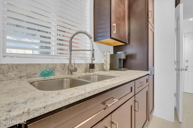 kitchen featuring light tile patterned flooring, light stone countertops, and sink