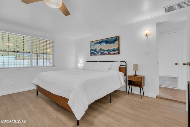 bedroom featuring brick wall, light hardwood / wood-style flooring, and ceiling fan