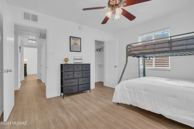 bedroom featuring ceiling fan, light hardwood / wood-style flooring, a closet, and a walk in closet