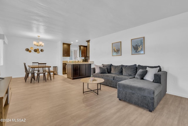 living room featuring an inviting chandelier, sink, and light hardwood / wood-style floors