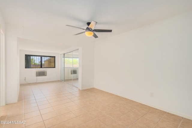 spare room with ceiling fan, light tile patterned flooring, and an AC wall unit