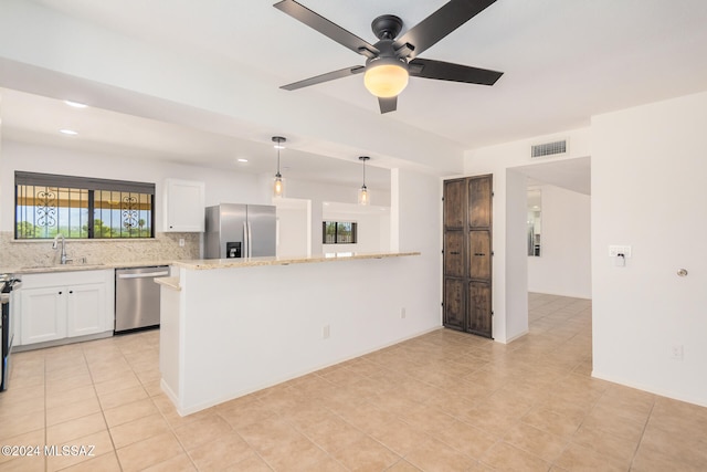 kitchen featuring hanging light fixtures, light stone counters, backsplash, appliances with stainless steel finishes, and white cabinetry